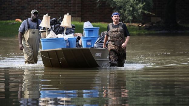 Dos hombres llevan una lancha con víveres durante la tormenta Harvey.