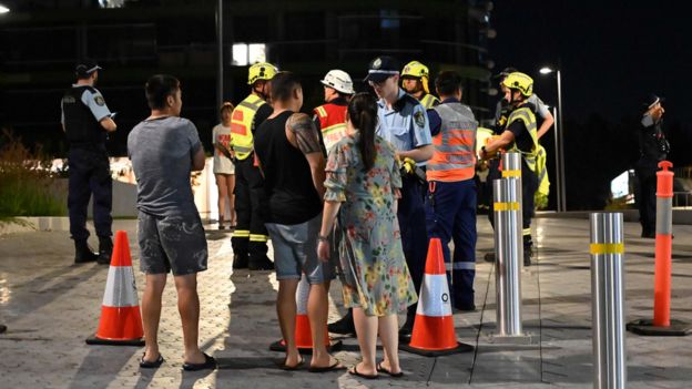 Police talk with evacuated residents from the Opal Tower on Monday