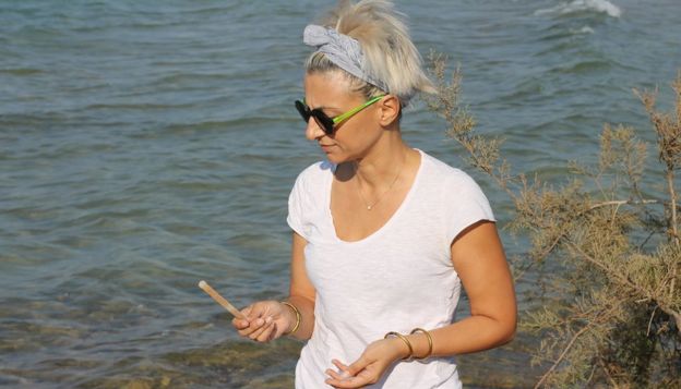 Zana Kontamanoli picks up glowstick on the beach