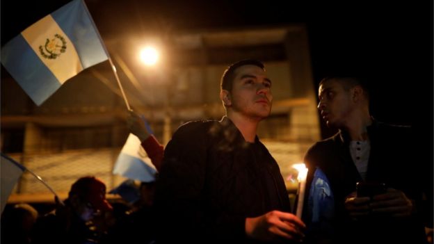 Hombres con velas y banderas en una vigilia en apoyo a la Cicig.