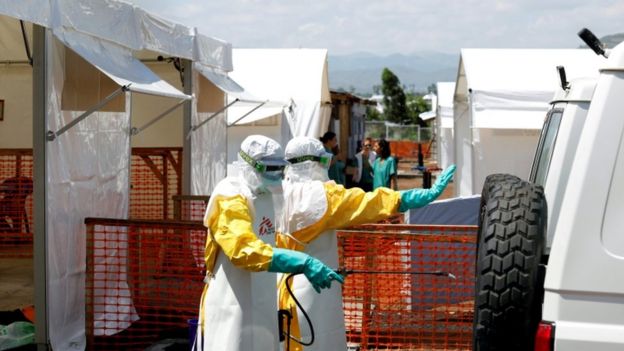Health workers dressed in protective suits disinfect an ambulance at an Ebola treatment centre in DR Congo