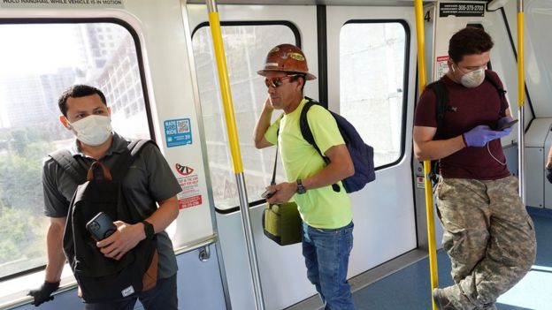 People, some wearing protective masks, ride the Metromover as they try to protect themselves against the coronavirus on 24 March 2020 in Miami, Florida.