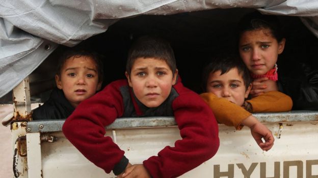 Syrian children sit in the back of a truck as they flee the fighting for Maarat al-Numan on 28 December 2019