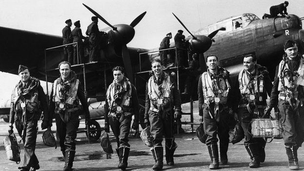 April 1943: The crew of a Lancaster bomber walk away from their plane after a flight while ground crew check it over.