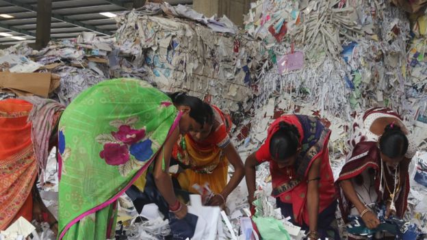 Women workers sort waste paper before it is recycled at a plant in Gujarat