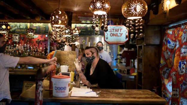 Bar staff check patrons' ID at Under the Volcano in Houston, Texas, on May 22, 2020