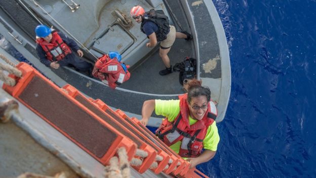 Tasha Fuiava, a US mariner who had been sailing for five months on a damaged sailboat, climbing on board the USS Ashland in the Pacific Ocean, 25 October 2017