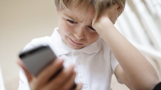 Niño llorando viendo su teléfono