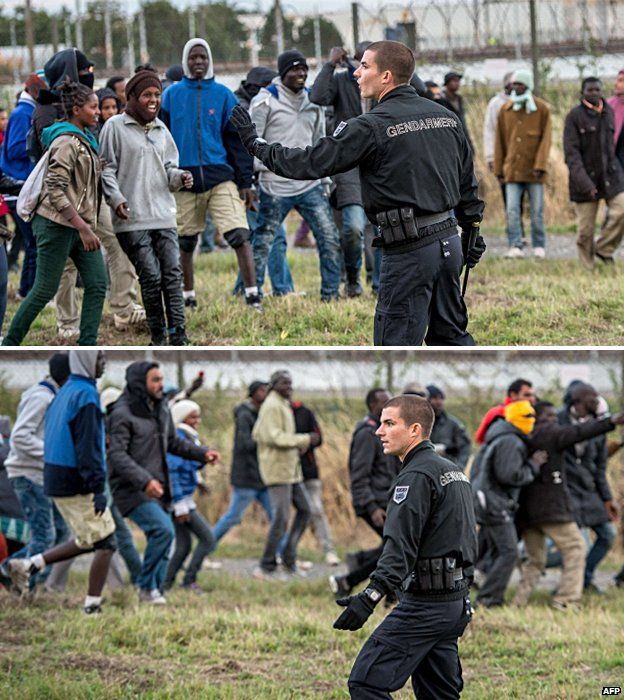 A French policemen trying to keep a group of migrants off a road near Calais