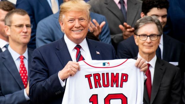 Donald Trump segurando uma camisa com o próprio nome