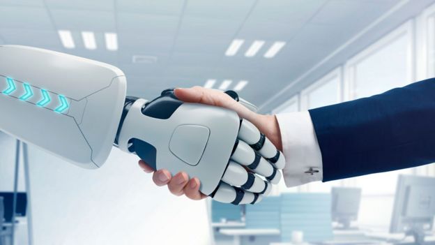 Un robot y un hombre se dan la mano