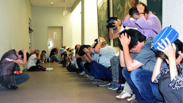 Residents cover their heads while taking shelter during an evacuation drill for North Korean missiles in Wajima, Ishikawa prefecture, 30 August 2017