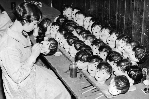 Un operaio che dipinge le bambole di celluloide testa in una fabbrica a Leicester nel 1935