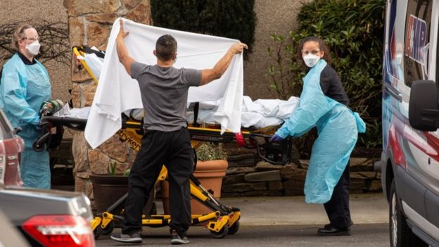 Healthcare workers transport a patient on a stretcher into an ambulance at Life Care Center of Kirkland in Kirkland, Washington