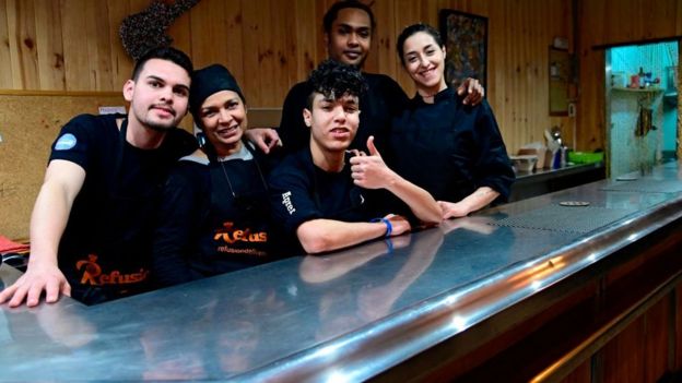 Migrantes de Venezuela, Sudán, Marruecos y Siria compartiendo la cocina del restaurante Refusión.