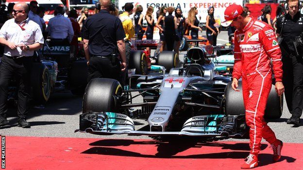 Sebastien Vettel looks at Lewis Hamilton's car