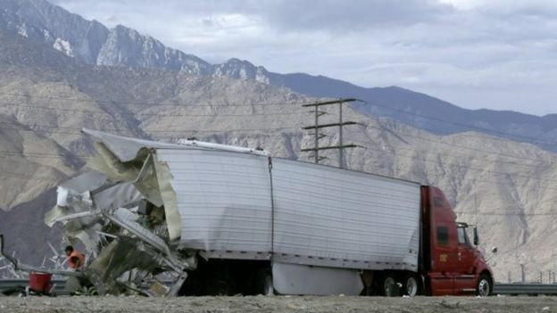 Workers and law enforcement personnel inspect a truck that was in collision with a tour bus on Interstate 10 near Palm Springs (23 October 2016)