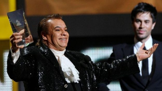 Juan Gabriel saluda con un premio en su mano.