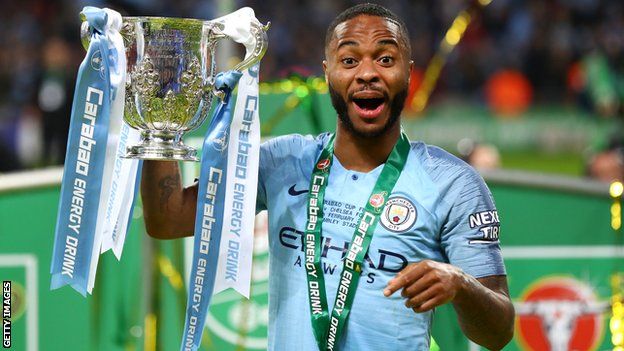 Manchester City forward Raheem Sterling smiles as he holds up the Carabao Cup trophy