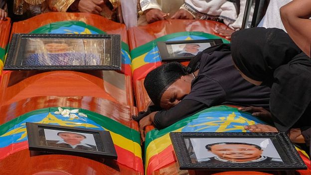 A woman lies on the coffin during a ceremony in memory of Ethiopian pbadengers and crew dead in the crash of Ethiopian Airways