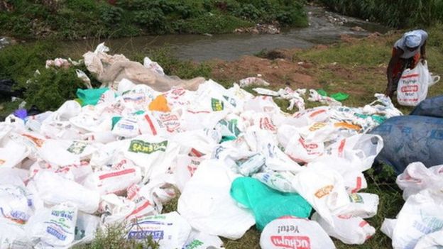 A woman sorts out used plastic bags for re-use at the shores of a river in Nairobi (24 June 2014)