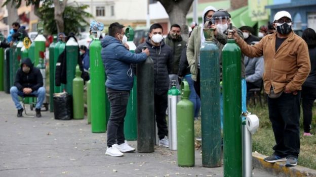 Gente haciendo fila con balones de oxígeno