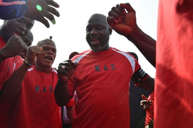 Liberia's president-elect and former football star George Weah (C) reacts with teammates prior to taking part in a friendly football match between Weah All Stars team and Armed Forces of Liberia team
