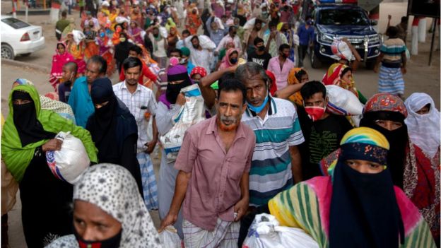 ঢাকায় একটি এলাকায় সাহায্য নিয়ে বাড়ি ফিরছে নিম্ন আয়ের মানুষ।