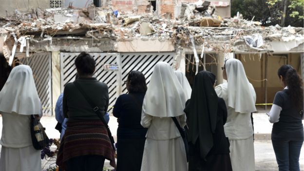 Varias mujeres, entre ellas religiosas, miran un edificio derrumbado en la Ciudad de México.