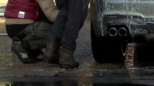 Hombres en un lavadero de autos, sólo piernas a la vista