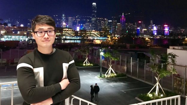 Simon Cheng stands against a city backdrop at night
