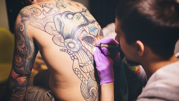 Man tattooing someone's back