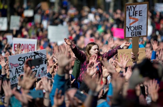 A young girl raises her hands with hundreds of others during the March for Our Lives rally on March 24, 2018 in Seattle.