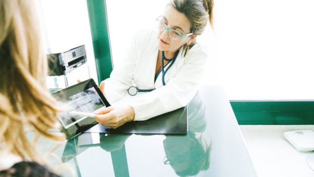 Una doctora muestra a una paciente un diagnóstico en un tableta