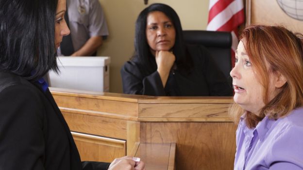 Un juge regarde une femme témoigner devant le tribunal.