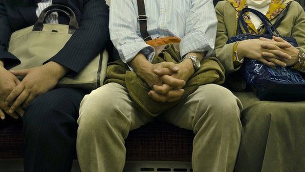 A man sitting between two others on a train