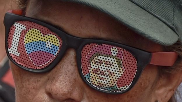 A supporter of Venezuelan President Nicolas Maduro wearing glasses depicting Venezuelan late President Hugo Chavez, attend a rally in Caracas on May 14, 2016.