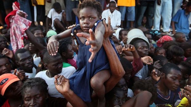 Una niña es levantada en brazos en medio de una multitud de gente en Haití.