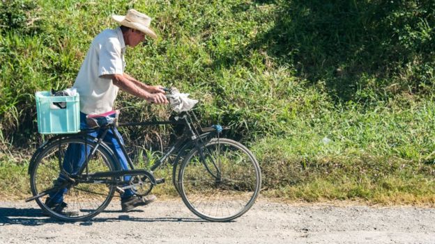 Un hombre lleva una bicileta en Cuba