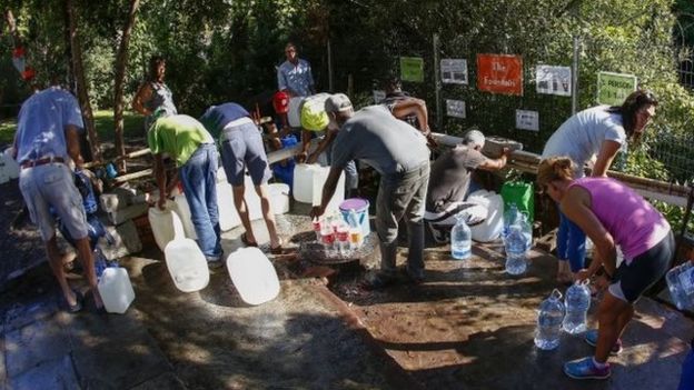 Un grupo de personas recoge agua de un manantial en Ciudad del Cabo.