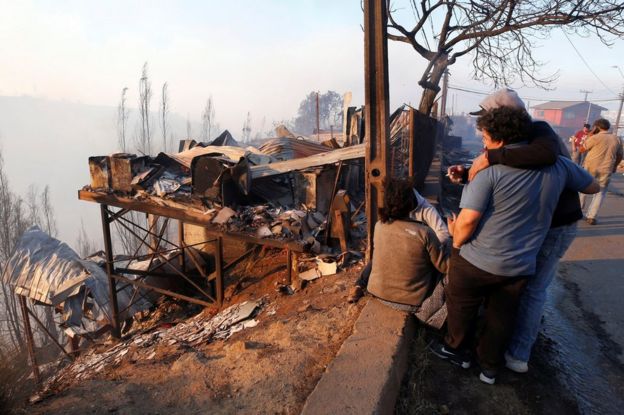 People react next to the debris of their house following the spread of wildfires in Valparaiso, Chile, 24 December 2019