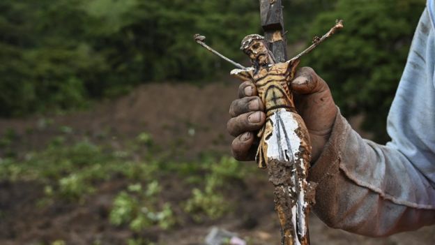 A man shows a Christ found in the mud after a landslide