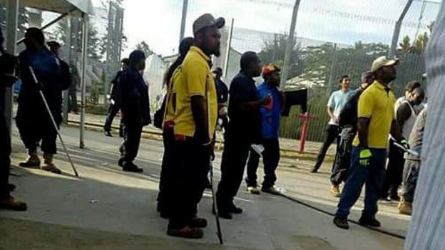 PNG police and immigration officials holding poles in the Manus detention centre