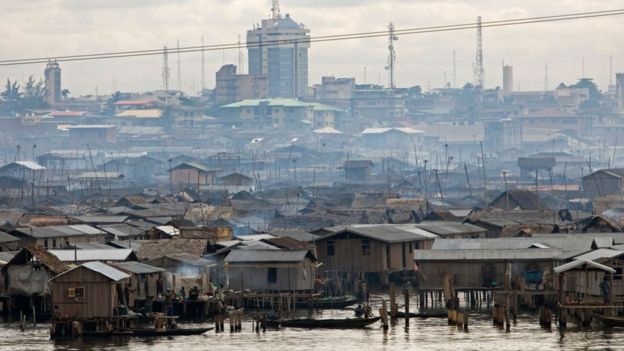 A view of lagoon-side huts in Lagos with high rise buildings in the background
