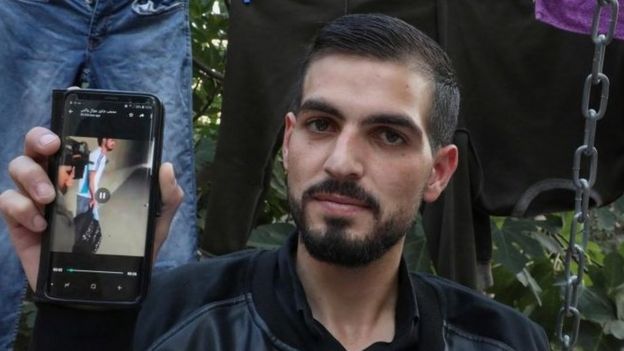 Qawasmi displays on his phone a video leaked online apparently showing a border guard shooting him in the back
