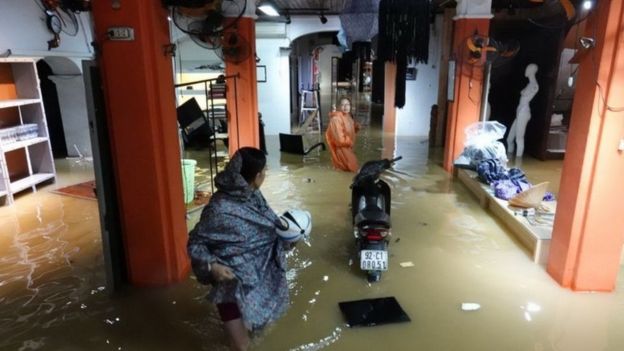 Local residents stand inside their flooded home in the tourist town of Hoi An, Vietnam (05 November 2017)