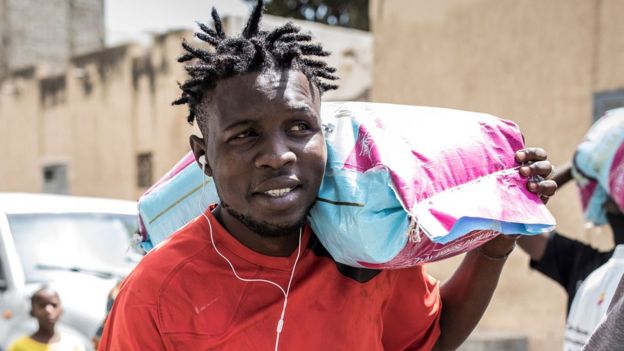 Un jeune sénégalais du comité des jeunes du quartier de Fann Hock, porte un sac de riz le 7 mai 2020 à Dakar, pour le distribuer aux familles qui ont besoin d'aide lors de l'épidémie de coronavirus COVID-19.