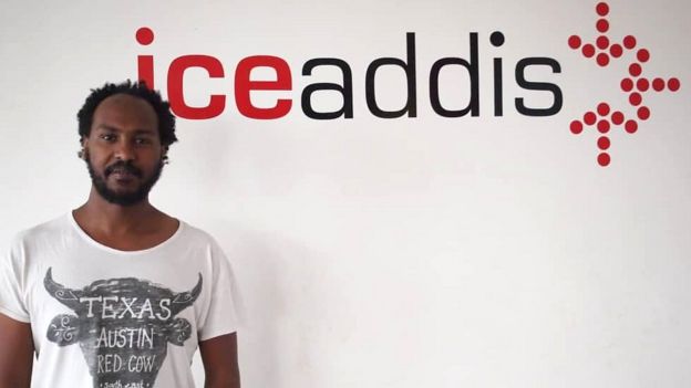 Markos Lemma in front of a logo for his co-working space IceAddis