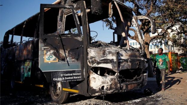 A supporter of the ruling ZANU-PF walks past a burnt vehicle at the party's offices a day after the clashes between security forces and opposition protesters in Harare, Zimbabwe, August 2, 2018