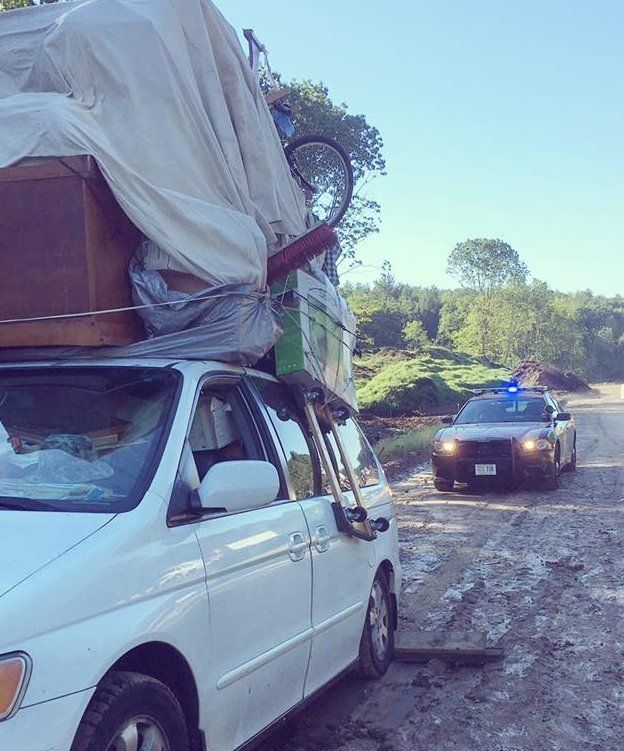 An image shows a van overloaded with items including a bicycle and other pieces of furniture.
